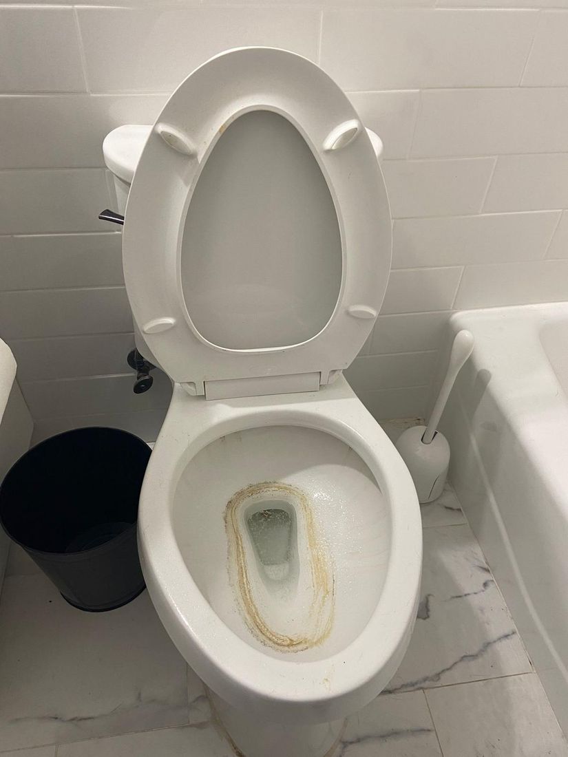 Toilet bowl with a heavy hard-water stain ring before cleaning