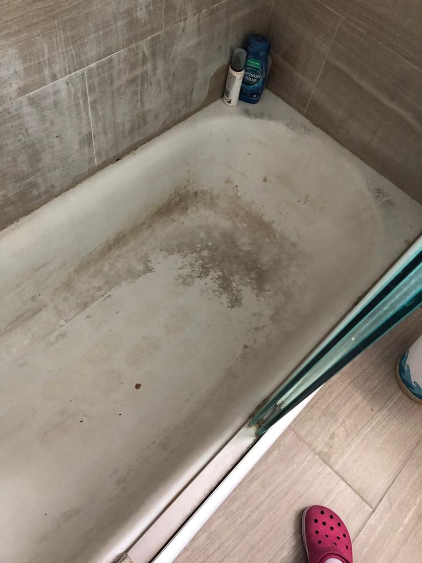 Bathtub covered in dark grime and soap scum before cleaning